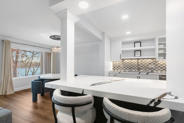 dining room with decorative columns, crown molding, hardwood / wood-style flooring, and sink