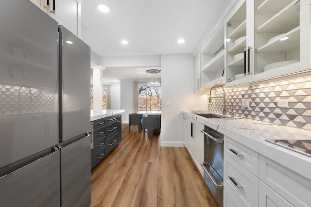 kitchen with a warming drawer, a sink, tasteful backsplash, white cabinetry, and freestanding refrigerator