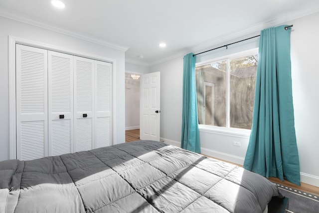 bedroom with hardwood / wood-style flooring, ornamental molding, and a closet