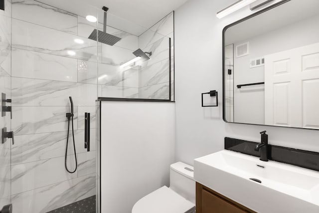 bathroom featuring vanity, toilet, and tiled shower