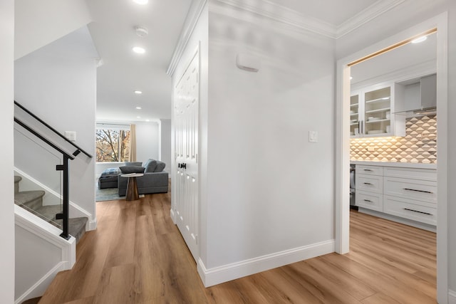 hallway featuring ornamental molding and light hardwood / wood-style floors