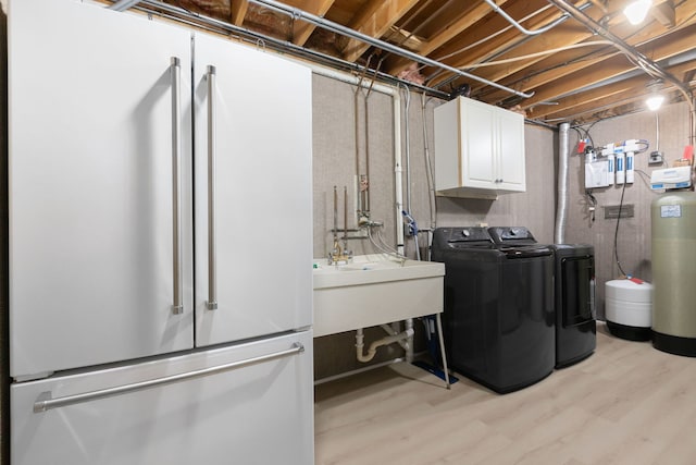 clothes washing area featuring cabinets, independent washer and dryer, sink, and light hardwood / wood-style floors