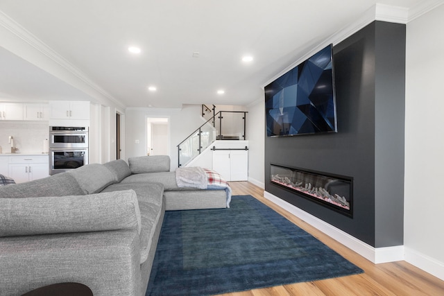 living room featuring ornamental molding, sink, and light hardwood / wood-style flooring