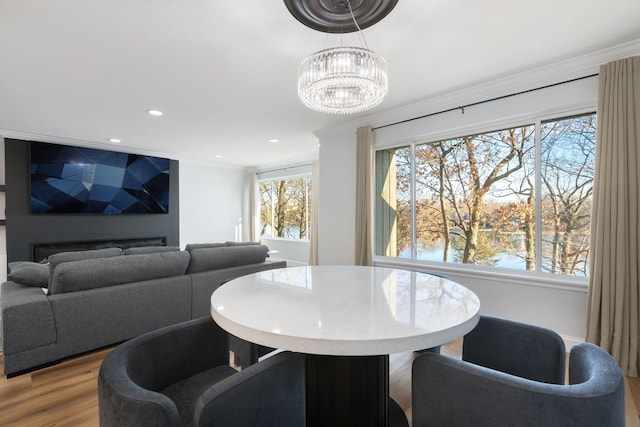 dining area with crown molding, a water view, and light hardwood / wood-style flooring