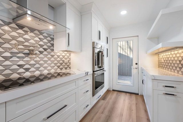 kitchen with white cabinetry, stainless steel double oven, tasteful backsplash, and light stone counters