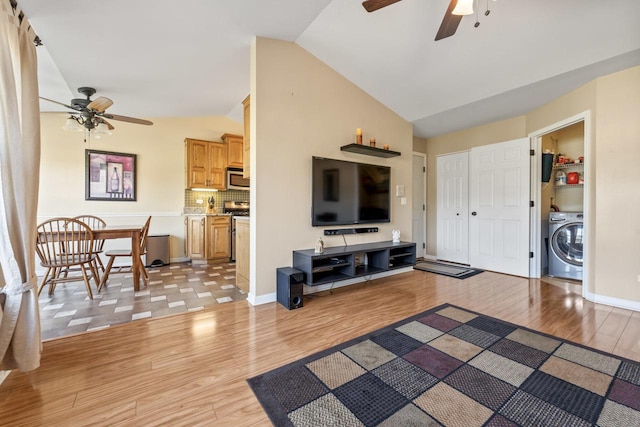 living room with ceiling fan, light wood-type flooring, vaulted ceiling, and washer / dryer