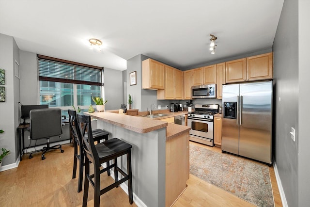 kitchen featuring light brown cabinets, a kitchen breakfast bar, sink, appliances with stainless steel finishes, and kitchen peninsula