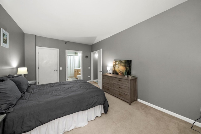 bedroom with connected bathroom and light carpet