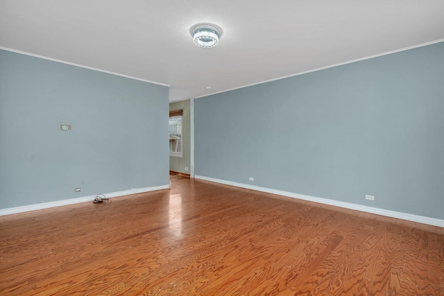 spare room with crown molding, baseboards, and wood finished floors