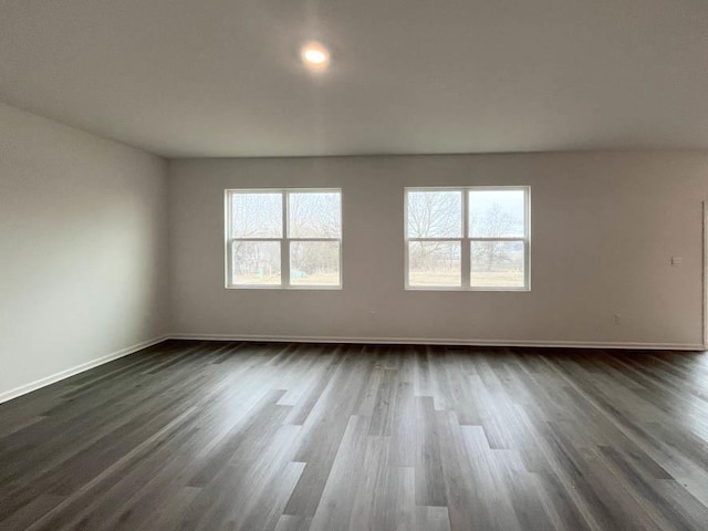 empty room featuring dark wood-type flooring and a healthy amount of sunlight