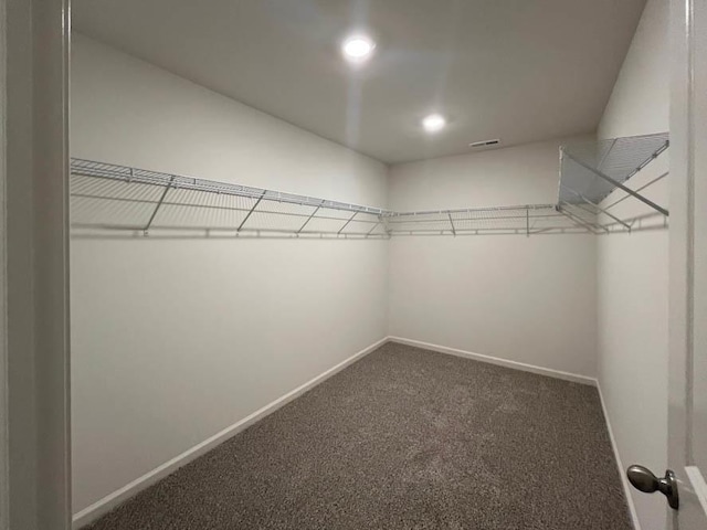 walk in closet featuring dark carpet