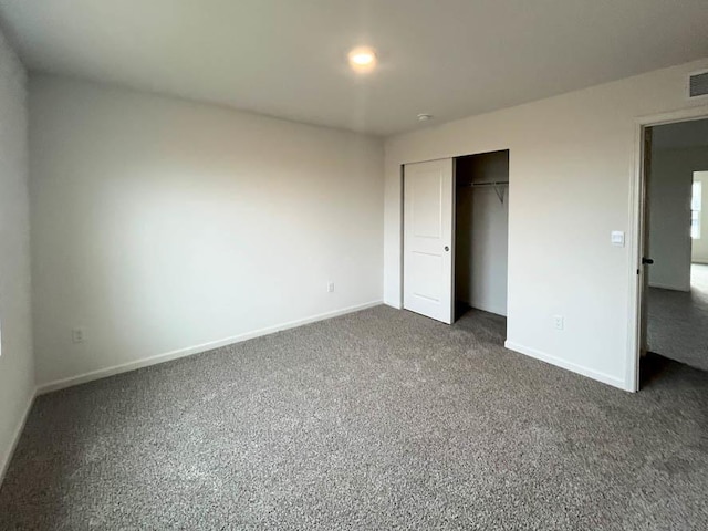 unfurnished bedroom with dark carpet and a closet