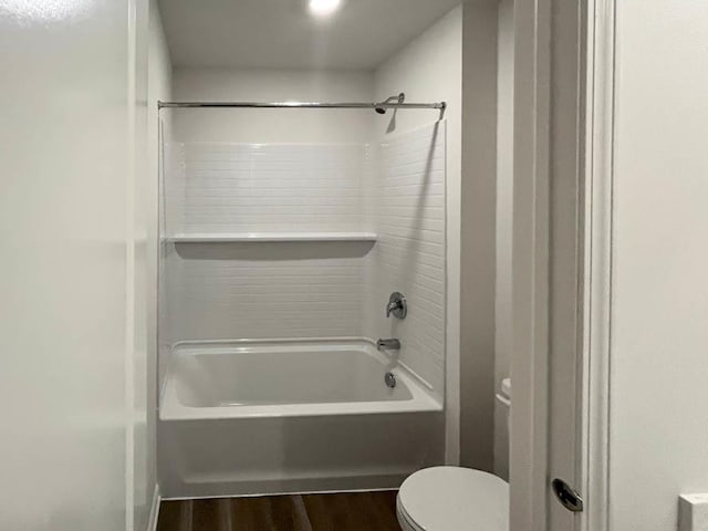 bathroom featuring hardwood / wood-style flooring, washtub / shower combination, and toilet