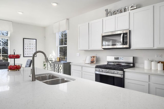 kitchen with appliances with stainless steel finishes, sink, and white cabinets