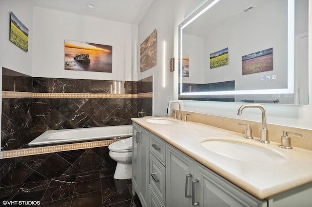 bathroom featuring tiled tub, vanity, and toilet