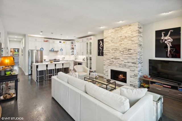 living room with dark hardwood / wood-style flooring, sink, and a fireplace