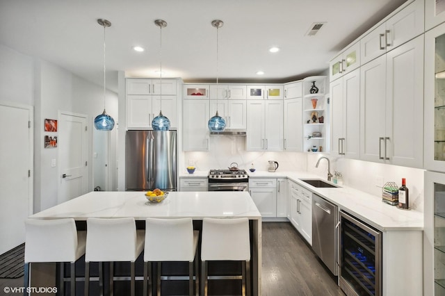 kitchen with sink, wine cooler, decorative light fixtures, a kitchen island, and appliances with stainless steel finishes