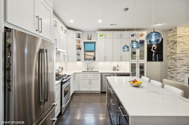 kitchen with appliances with stainless steel finishes, tasteful backsplash, a breakfast bar, white cabinetry, and hanging light fixtures