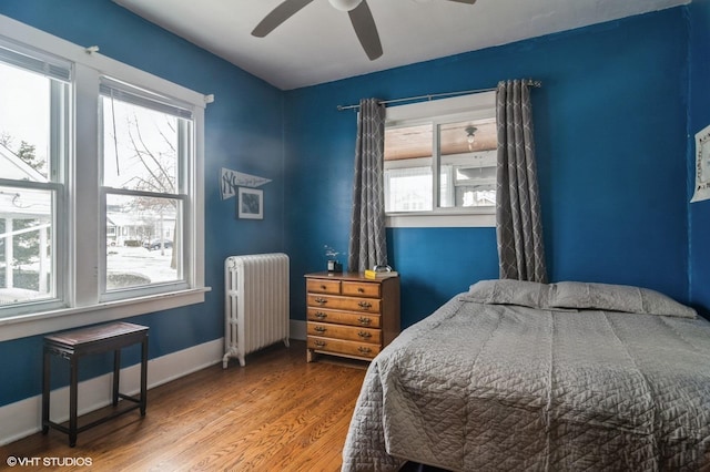 bedroom featuring radiator heating unit, ceiling fan, and hardwood / wood-style floors