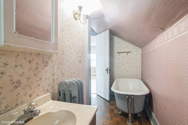 bathroom featuring vanity, a bathtub, parquet floors, and vaulted ceiling