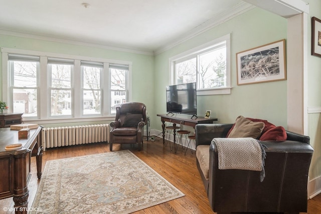 sitting room with hardwood / wood-style floors, radiator heating unit, and ornamental molding