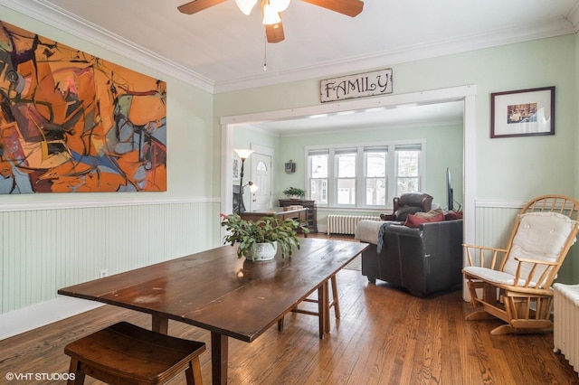 dining space with hardwood / wood-style floors, radiator heating unit, ceiling fan, and ornamental molding