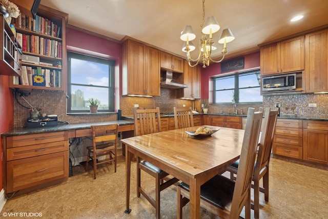 dining space with sink, built in desk, and a notable chandelier