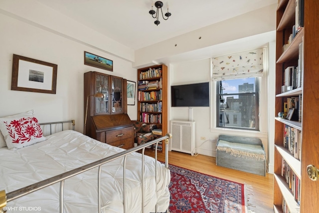 bedroom with radiator heating unit and wood-type flooring