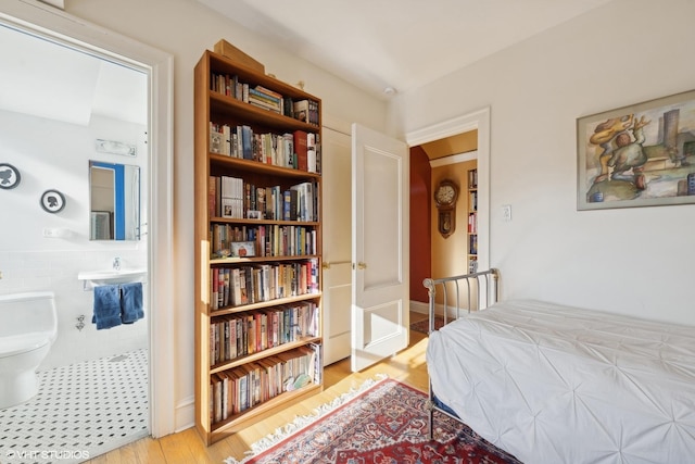 bedroom with light hardwood / wood-style flooring and tile walls