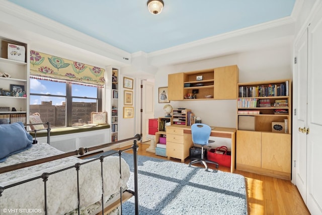 bedroom featuring ornamental molding, radiator, and light hardwood / wood-style floors