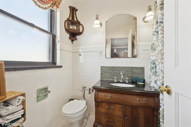 bathroom with tile patterned flooring, vanity, tile walls, and toilet