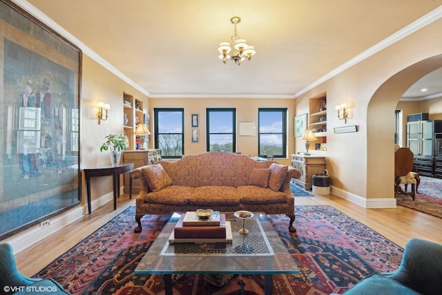 living room with ornamental molding, an inviting chandelier, and light hardwood / wood-style flooring