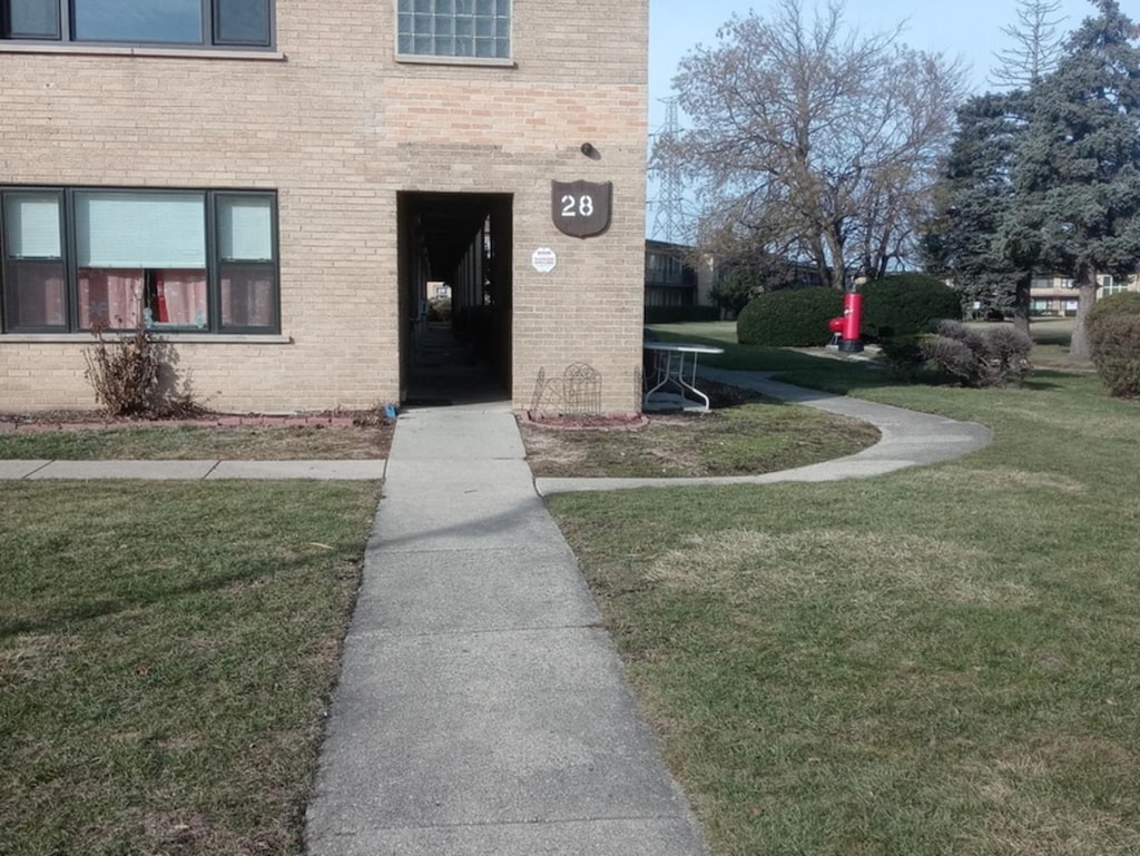 view of exterior entry featuring a lawn