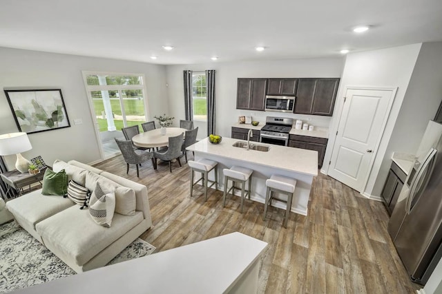 kitchen featuring a breakfast bar, stainless steel appliances, light hardwood / wood-style floors, and an island with sink