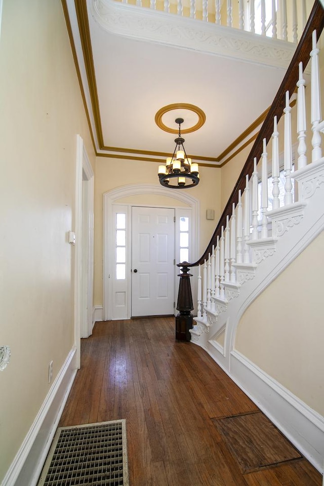 entrance foyer with wood-type flooring, crown molding, and a chandelier