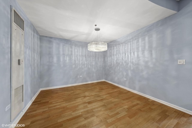 spare room featuring a chandelier and hardwood / wood-style flooring