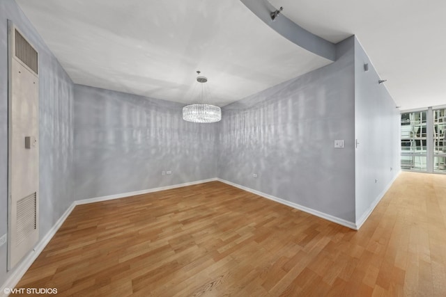 empty room featuring hardwood / wood-style floors and a notable chandelier