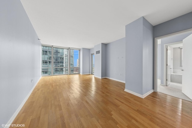 unfurnished living room featuring floor to ceiling windows and light hardwood / wood-style flooring