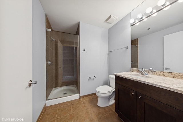 bathroom featuring tile patterned flooring, vanity, toilet, and walk in shower