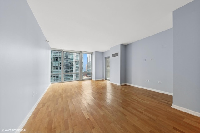 empty room featuring floor to ceiling windows and light hardwood / wood-style flooring