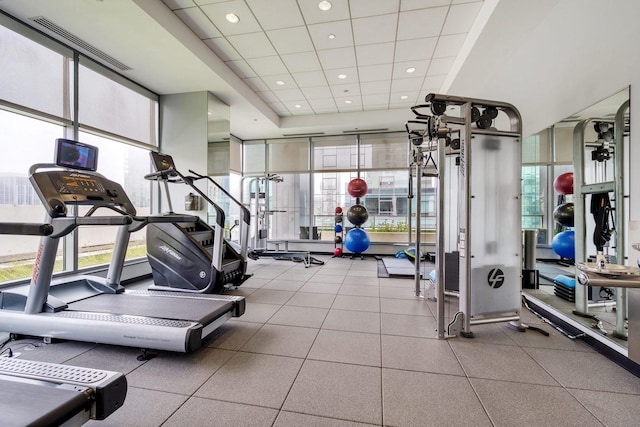 workout area featuring a drop ceiling, expansive windows, and a wealth of natural light