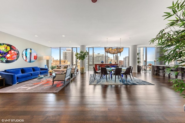 living room with dark hardwood / wood-style floors, a healthy amount of sunlight, a wall of windows, and a chandelier