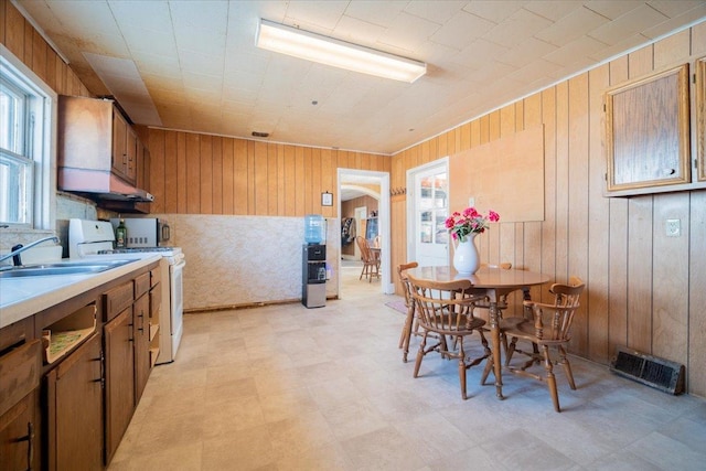 kitchen featuring sink, wooden walls, and white stove