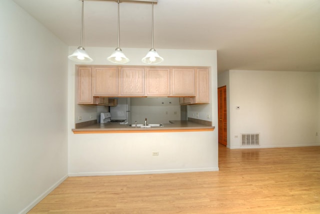 kitchen featuring light brown cabinets, sink, decorative light fixtures, white stove, and light wood-type flooring