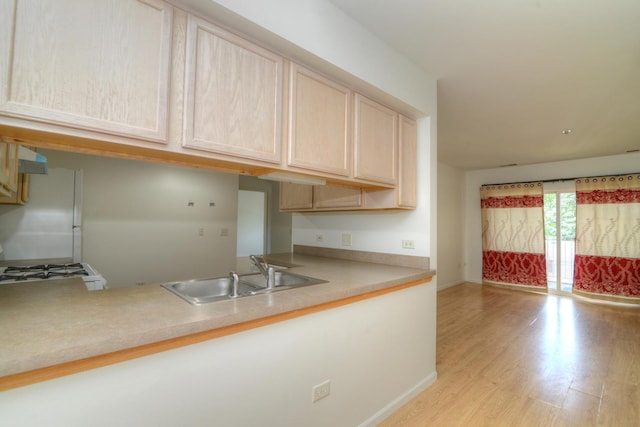 kitchen with sink, light brown cabinets, stove, white fridge, and light hardwood / wood-style floors