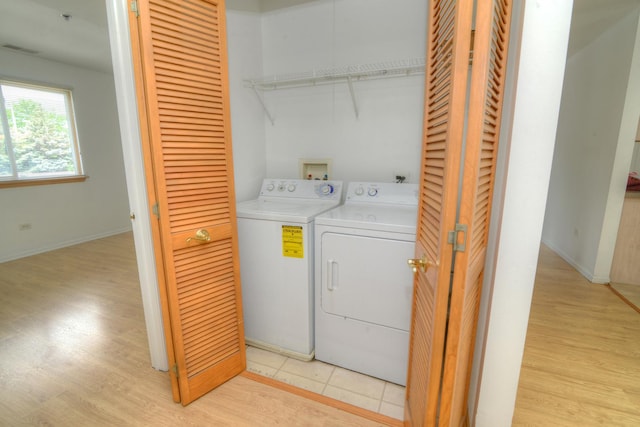 clothes washing area with washing machine and dryer and light tile patterned floors