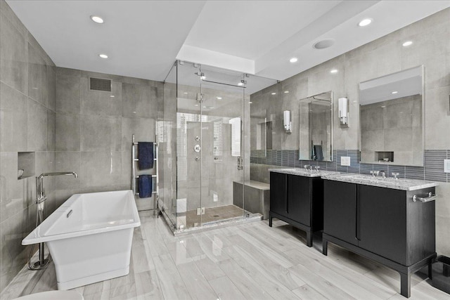 bathroom featuring separate shower and tub, vanity, and tile walls