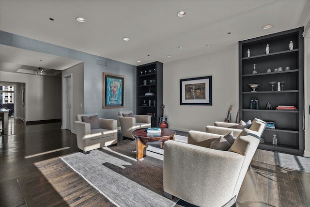 living room featuring ceiling fan, built in features, and dark hardwood / wood-style floors