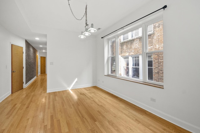 empty room with a chandelier and light wood-type flooring