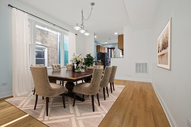 dining area featuring a notable chandelier and light wood-type flooring